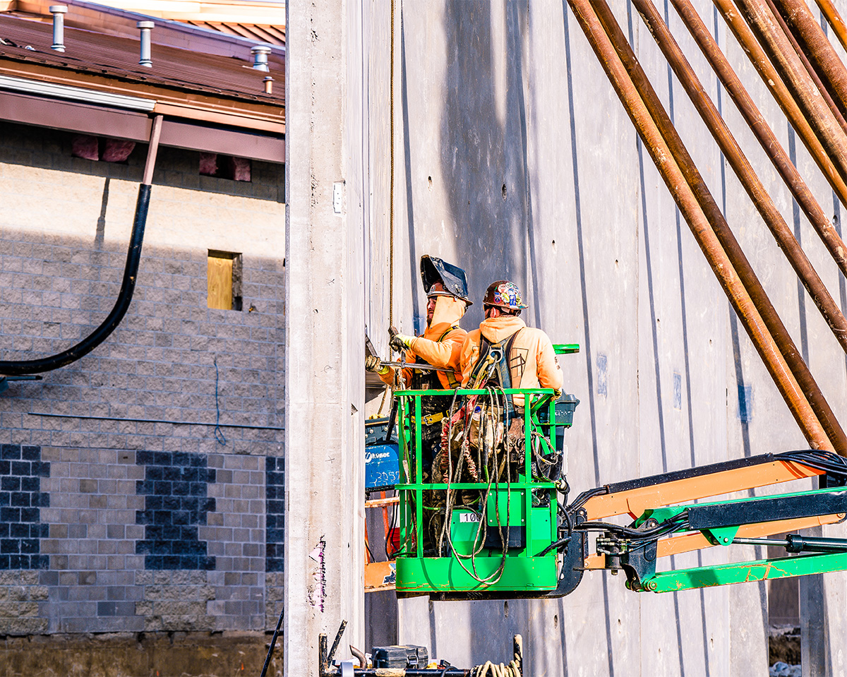 two men in lift inspecting steel structural element